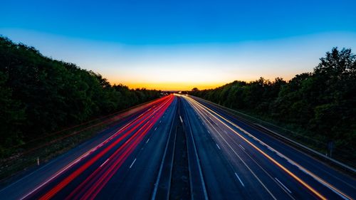 Light trails on highway against sky at sunset