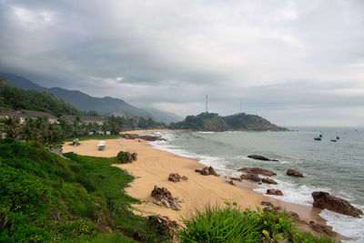 Scenic view of beach against cloudy sky