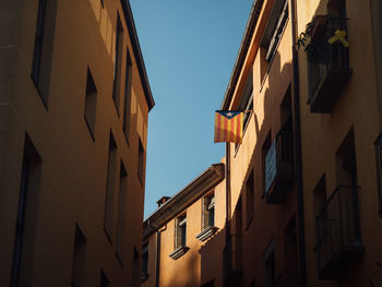 Low angle view of buildings with a catalan flag hanging out of the window against clear sky