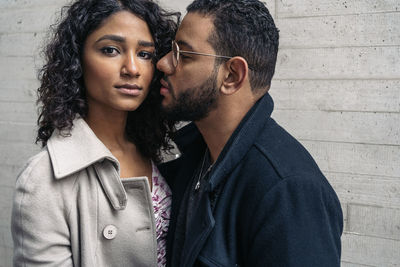 Man kissing woman against wall