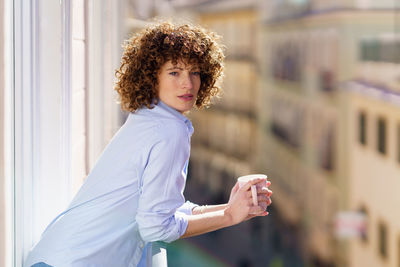 Portrait of young woman standing against building