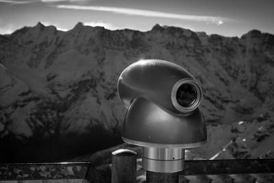 Close-up of coin-operated binoculars against mountains