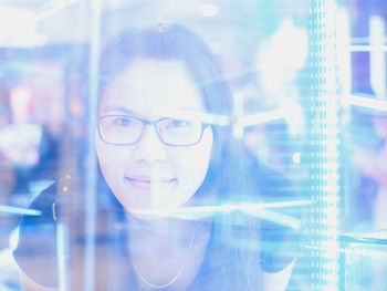 Portrait of smiling young woman seen through glass window