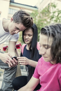 High school friends reading text message on mobile phone in high school schoolyard