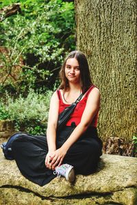 Young woman sitting on tree trunk