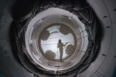 Centered view of man standing in tunnel spraying paint