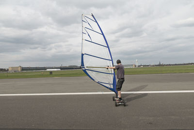 Rear view of man windsurfing on runway