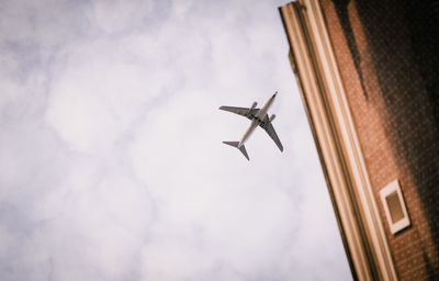 Low angle view of airplane flying against sky