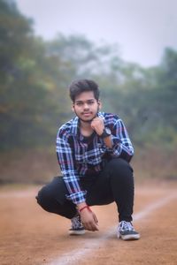 Portrait of young man crouching outdoors