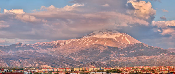 Aerial view of townscape by mountain against sky