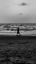 Silhouette man on beach against sky