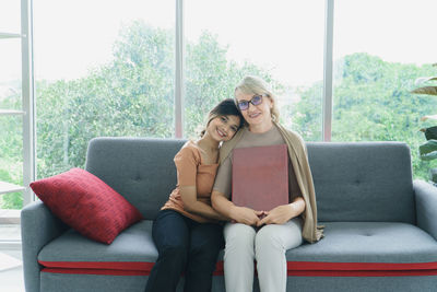 Young woman sitting on sofa against window