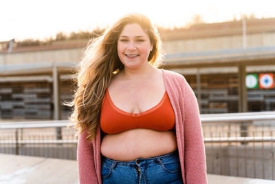 Portrait of young woman standing against building