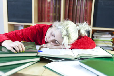 Young woman sleeping on desk while studying in library