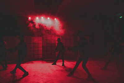 Silhouette people standing by illuminated lights at night