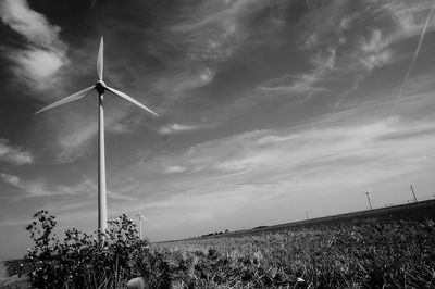 Low angle view of wind turbines in field