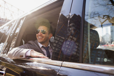 Young businessman looking out the window sitting in car service limousine