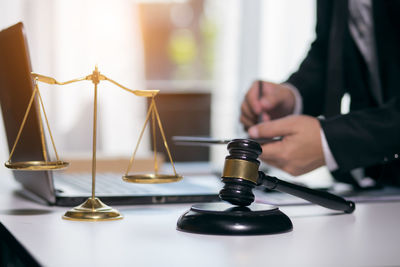 Close-up of hand holding clock on table