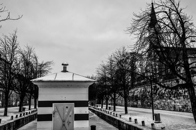 Bare trees and buildings against sky during winter