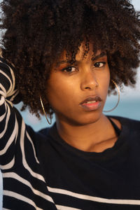 Young black woman standing by the sea wearing striped jumper