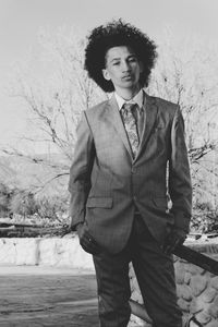 Portrait of man in suit standing against bare tree