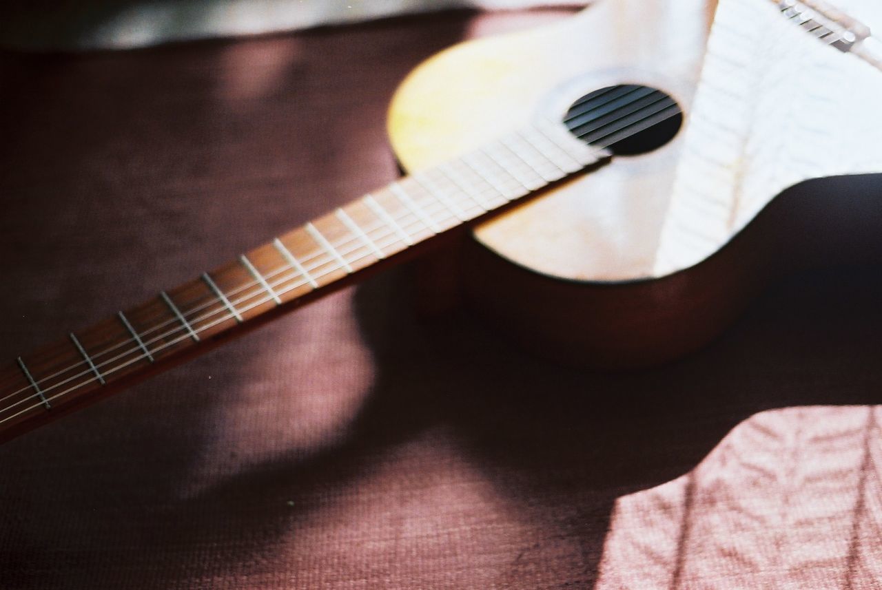 musical instrument, music, indoors, guitar, arts culture and entertainment, musical instrument string, musical equipment, close-up, high angle view, hobbies, acoustic guitar, skill, part of, string instrument, selective focus, still life, cropped, person