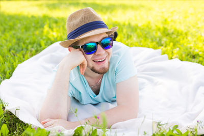 Young woman wearing sunglasses sitting on field against plants