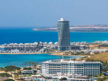 High angle view of city by sea against clear blue sky