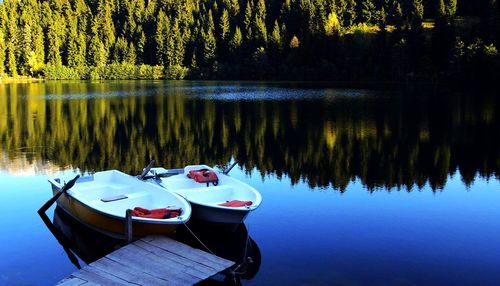 Boats moored by jetty at calm lake