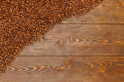 Roasted coffee beans laid on the brown wooden table surface