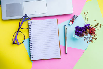 Spiral notebook with laptop on colorful papers