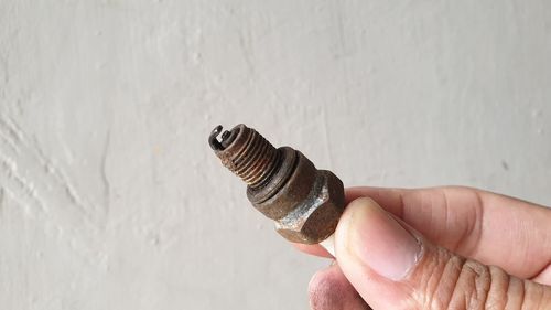 Close-up of hand holding stick against wall