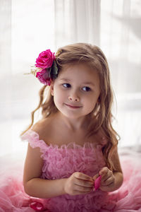 Portrait of a girl in a pink dress and a flower with a rose in her head in the studio