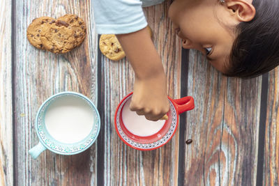 High angle view of girl holding cookies on wooden table