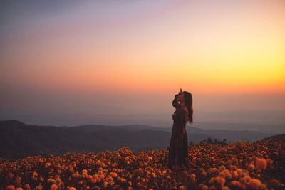 Man standing on field against sky during sunset