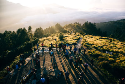 High angle view of people on green mountain during sunny day