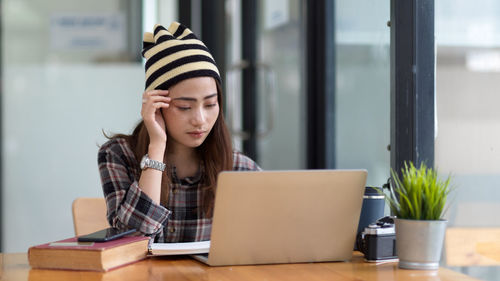 Young woman using laptop while sitting on table