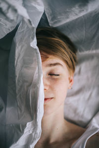 Close-up of young woman hiding behind curtain