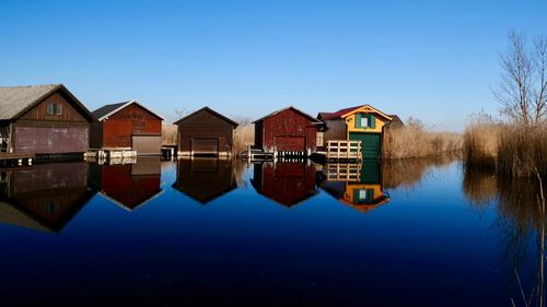 Reflection of buildings on lake against clear sky