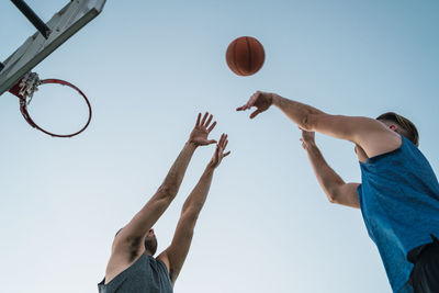 Low angle view of men playing basketball against sky