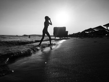 Side view of a silhouette woman walking on beach