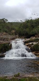 Scenic view of waterfall against sky