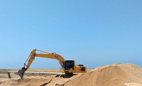 Digger on construction site against clear sky