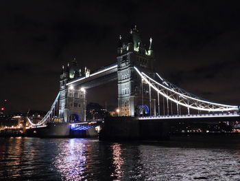 Illuminated bridge over river at night