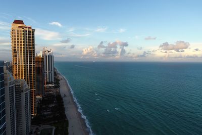 Sea by modern buildings against sky