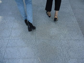 Low section of friends walking on footpath