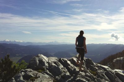 Rear view of man standing on rock against sky