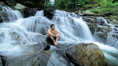 Full length of man waterfall on rock in forest