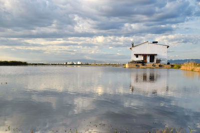 Building by lake against sky