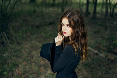 Young woman standing against trees